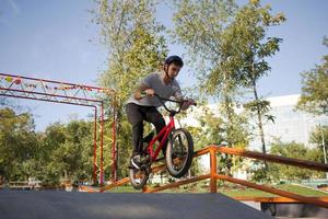 Bmx rider entrenando y haciendo trucos en street plaza, bicyxle stunt rider en cocncrete skatepark foto