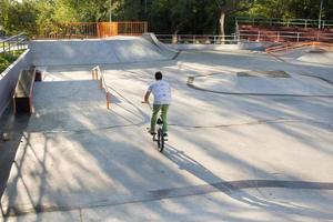 Bmx rider entrenando y haciendo trucos en street plaza, bicyxle stunt rider en cocncrete skatepark foto