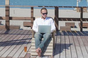 young men with laptopp working near the pool, freelancer in hotel on vacation with notebook photo