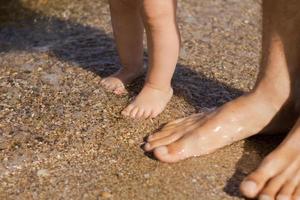 Close up picture of father with one year kid walking on the beach at summertime photo