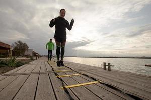 group of young people training outdoors, runners exercises, sea or river background photo