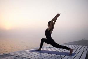 mujer joven posando en yoga asans, fondo de mar matutino foto
