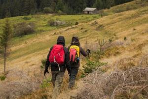 pareja joven excursionistas con tazas termos en el bosque, viajeros en mauntains bebiendo té o café foto