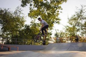 Bmx rider entrenando y haciendo trucos en street plaza, bicyxle stunt rider en cocncrete skatepark foto