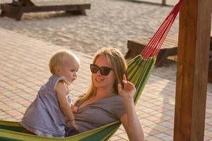 joven madre relajándose con su hija en una hamaca en la playa foto