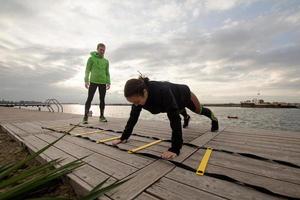 group of young people training outdoors, runners exercises, sea or river background photo