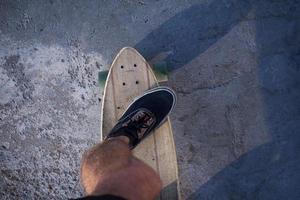 Young bearded man riding on skateboard, hipster with longboard in red shirt and blue jeans urban background photo