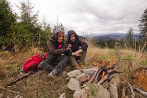 Young couple hikers with thermos cups in forest, travelers in mauntains drinking tea or coffee photo