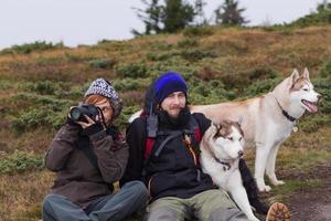 young couple with husky dogs in mountains, travel with dogs photo