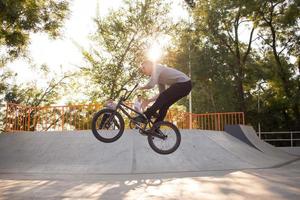 Bmx rider entrenando y haciendo trucos en street plaza, bicyxle stunt rider en cocncrete skatepark foto