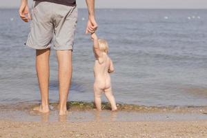 Close up picture of father with one year kid walking on the beach at summertime photo