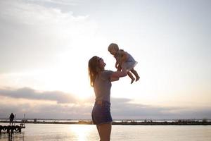 madre e hija caminando en el muelle de madera en un día soleado, familia feliz en la playa foto