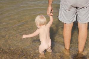 Close up picture of father with one year kid walking on the beach at summertime photo