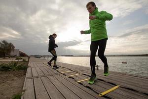 group of young people training outdoors, runners exercises, sea or river background photo