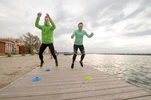 group of young people training outdoors, runners exercises, sea or river background photo