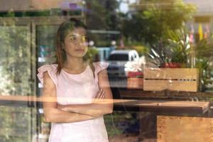 The woman stands and arms crossed in the glass room. photo