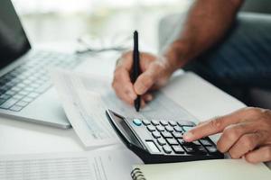 Man is calculating annual tax with calculator and filling form of Individual Income Tax Return. Season to pay Tax and Budget planning concept. photo