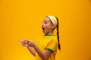 hincha de fútbol, equipo de brasil. Copa Mundial. hermosa niña animando a su equipo con fondo amarillo foto