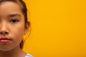 Beautiful asian girl sitting on yellow background. Happy little Asian girl smiling. photo