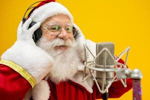 Santa Claus singing or speaking in a studio microphone. Merry Christmas. Broadcaster. Announcer. Promotion. Christmas music concept.
