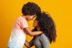 retrato de una joven madre afroamericana con un hijo pequeño. fondo amarillo familia brasileña.