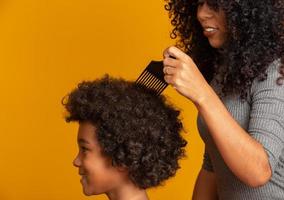 jóvenes afroamericanos peinándose aislados. tenedor para peinar el cabello rizado. fondo amarillo foto