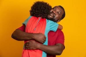 padre africano e hijo jugando al superhéroe durante el día. gente divirtiéndose fondo amarillo. concepto de familia amistosa. foto