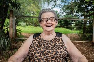 anciana granjera feliz con anteojos sonriendo y mirando a la cámara foto