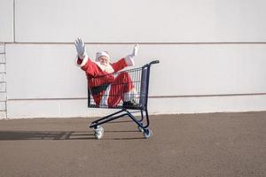 carro de supermercado con santa claus dentro. compras por concepto de navidad. foto