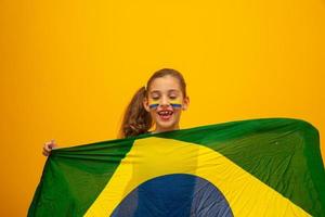 hincha de fútbol, equipo de brasil. Copa Mundial. hermosa niña animando a su equipo con fondo amarillo foto