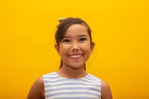hermosa chica asiática sentada sobre fondo amarillo. niña asiática feliz sonriendo. foto