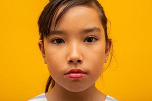 Beautiful asian girl sitting on yellow background. Happy little Asian girl smiling. photo