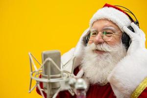 Santa Claus singing or speaking in a studio microphone. Merry Christmas. Broadcaster. Announcer. Promotion. Christmas music concept. photo