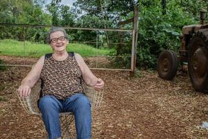 anciana granjera feliz con anteojos sonriendo y mirando a la cámara foto