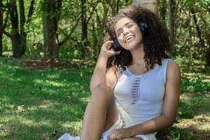 Beautiful afro american girl listening music in a park photo