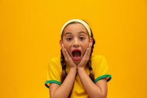 Football supporter, Brazil team. World Cup. Beautiful little girl cheering for her team on yellow background photo