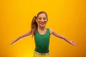 hincha de fútbol, equipo de brasil. Copa Mundial. hermosa niña animando a su equipo con fondo amarillo foto