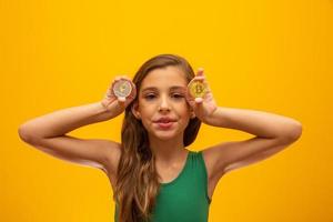 Child holding cryptocurrency in metal. Gold coin. Golden. On yellow background. photo