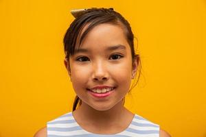 hermosa chica asiática sentada sobre fondo amarillo. niña asiática feliz sonriendo. foto