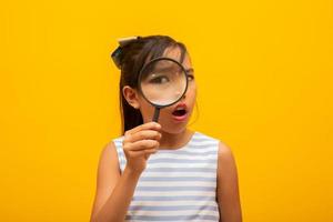 Portrait of happy little Asian child with magnifying glass. photo