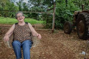 anciana granjera feliz con anteojos sonriendo y mirando a la cámara foto