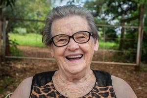 anciana granjera feliz con anteojos sonriendo y mirando a la cámara foto