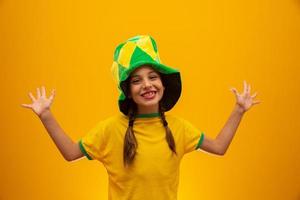 hincha de fútbol, equipo de brasil. Copa Mundial. hermosa niña animando a su equipo con fondo amarillo foto