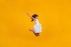 hermosa chica asiática sentada sobre fondo amarillo. niña asiática feliz sonriendo. foto