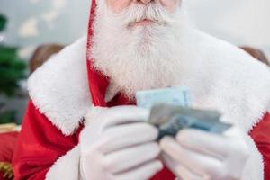 santa claus ofreciendo un regalo y dinero a la cámara. recibiendo regalos de navidad. fiestas de año nuevo. foto