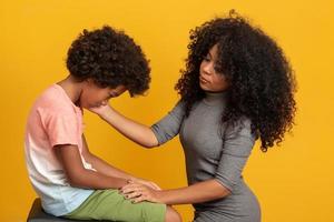 Caring worried african american mother holding hand of sad little mixed race son talking giving support and comfort, black mom foster parent consoling kid. photo