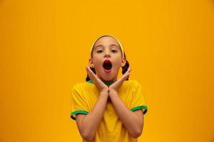 Football supporter, Brazil team. World Cup. Beautiful little girl cheering for her team on yellow background photo