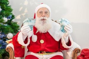 Santa Claus counting Brazilian money bills. Real Notes. 100 Reais notes. Savings concept for the end of the year. Spending over Christmas. Spent on Christmas presents. photo