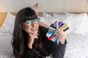Beautiful woman holding a hand multiple credit cards on the bed. Plastic money, electronic money and digital money will change the global marketing in the near future. Concept of rich woman. photo