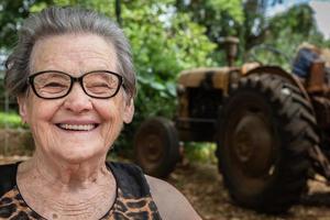 anciana granjera feliz con anteojos sonriendo y mirando a la cámara
